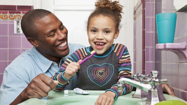 Padre che insegna alla figlia come lavarsi i denti