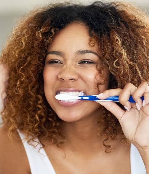 woman in mirror brushing her teeth