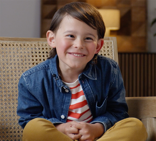 a boy smiling brightly sitting down